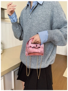 Détail macro du mini sac rose en cuir verni avec nœud élégant et chaîne dorée