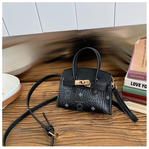 Détail d'un mini sac ours en cuir avec fermoir rotatif doré sur surface en bois