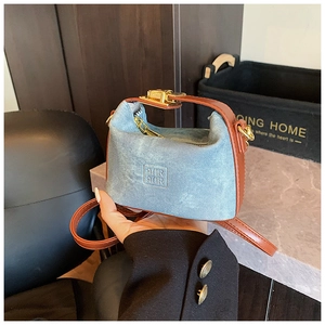 Detail of a kids denim shoulder bag with brown leather handles and gold metal hardware