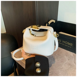 Detail of white lychee leather mini handbag with gold rotating lock and embossed logo