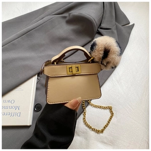 Close-up of mini leather handbag charm with leopard pompom and gold chain detail