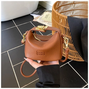 Detail of mini brown lychee pattern leather handbag with gold twist lock and handle