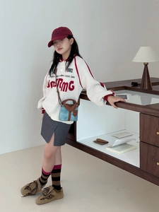 Detail of child's red URMG letter jacquard sweater with stylish crossbody bag