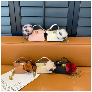 Detail of five colorful mini crossbody bags with fluffy pompons and golden metal chains