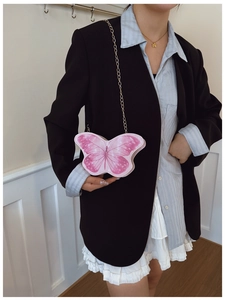 Détail d'un sac bandoulière rose en forme de papillon avec chaîne dorée pour enfant