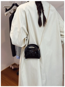 Vue détaillée du mini sac en cuir verni noir avec nœud papillon et chaîne dorée