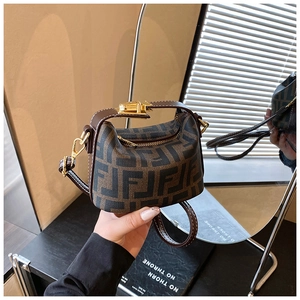 Detail of small brown monogram tote bag with leather handles and golden metal buckle