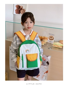 Girl wearing a color-block rainbow backpack in a cozy bakery shop setting