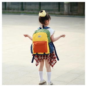 Rear side view of a child wearing a colorful color-block school backpack outdoors