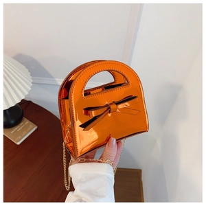 Détail du sac à main pour filles en cuir verni orange vif avec nœud et chaîne dorée