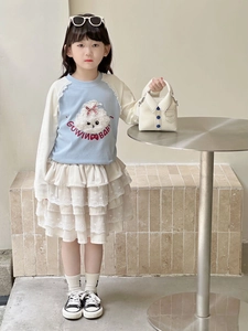 Detail of girls' blue sweatshirt with plush animal patch and tiered lace cake skirt