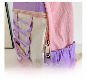 Detail of pink and purple backpack showing smooth metal zippers and elastic side pocket