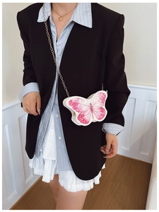 Detail of a white butterfly crossbody bag with pink wings and a gold chain strap
