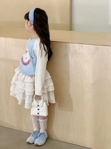 Detail of girl's blue sweatshirt, white lace cake skirt, and shirt-style mini handbag