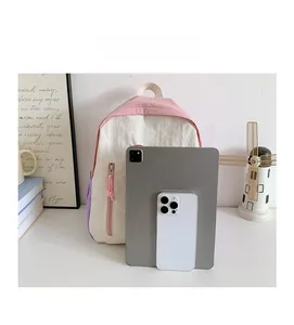 Mini color-block backpack size comparison with tablet and phone showing its small compact size