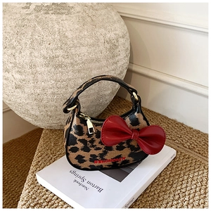 Détail du mini sac léopard avec un grand nœud rouge et une fermeture éclair dorée