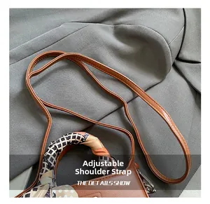 Dettaglio della tracolla regolabile e del manico in foulard di seta della borsa in pelle marrone