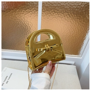 Détail du mini sac doré brillant avec nœud papillon 3D et bandoulière chaîne chic