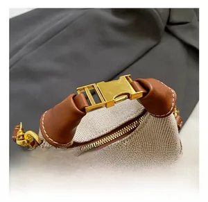 Macro detail of brown leather handle and gold metal hardware on beige fabric handbag