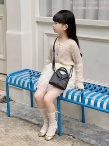 Detail of creative suit-style black crossbody bag on a little girl in an outdoor setting