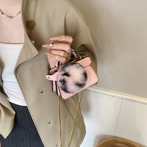 Mini pink shoulder bag for kids featuring a fluffy pompom and gold chain strap