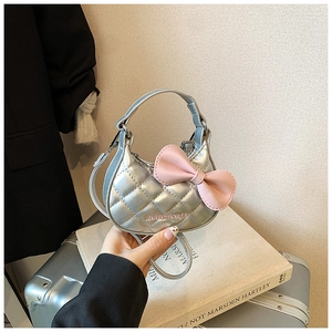 Détail d'un mini sac à main matelassé argenté avec nœud rose et bandoulière enfant
