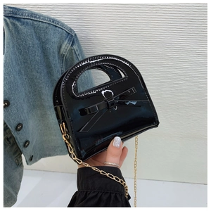 Détail d'un mini sac fille en cuir verni noir brillant avec nœud doux et chaîne dorée
