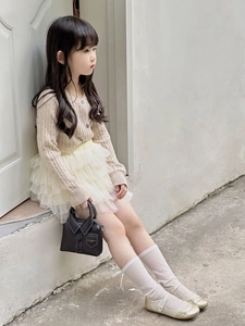 Detail of beige cable knit cardigan and tiered mesh tutu skirt set for toddler girls