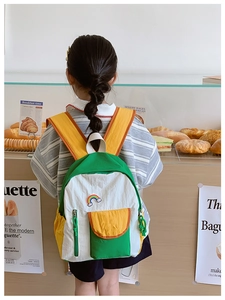 Rear view of a child wearing a colorful rainbow schoolbag in a cozy bakery setting
