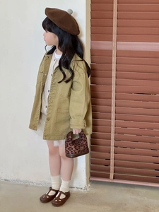 Detail of khaki canvas jacket showing large pockets and vintage buttons on girl's coat