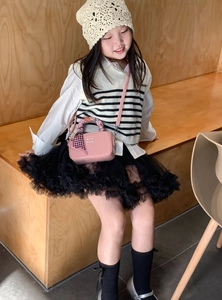Dettaglio della mini borsa rosa con manico in seta e fiocco indossata da bambina