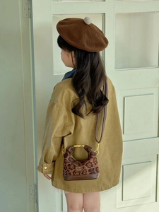 Detail of leopard print toddler mini crossbody bag with metal handle and brown leather base