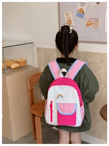 Close-up of rainbow embroidery detail and multi-pocket design on kids backpack