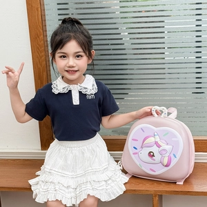 Pink heart-shaped 3D backpack with cartoon unicorn detail on child model in cozy setting