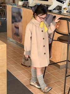 Detail of khaki toddler trench coat with classic lapel and plaid cuffs in a cafe