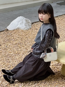 Dettaglio ravvicinato di una mini borsa in pelle bianca da bambina con foulard decorativo