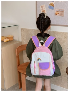Rear view of a child wearing a colorful rainbow schoolbag in a cozy bakery setting