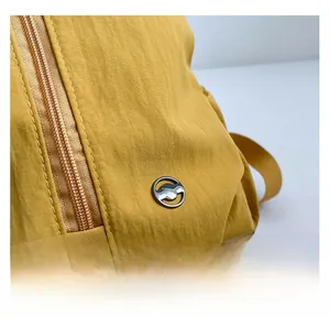 Detail view of bright yellow backpack fabric texture and metal zipper with logo