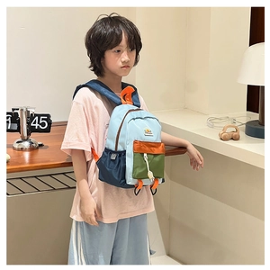Toddler modeling a colorful color-block school backpack in a cozy indoor setting
