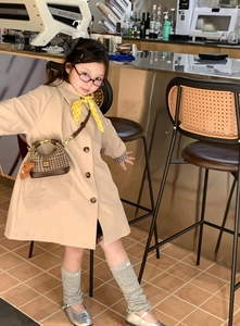 Detail of a beige girl's trench coat paired with a leopard print shoulder bag