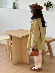 Dettaglio di una mini borsa marrone con foulard su una giacca retrò per bambina