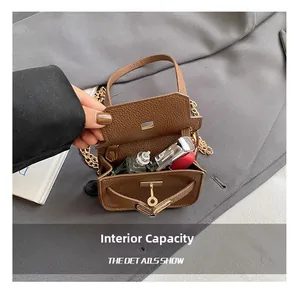 Détail de l'intérieur du mini sac en cuir marron avec rouge à lèvres et petit parfum