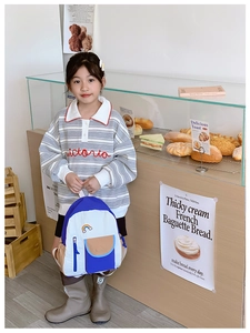 Detail of blue and white contrast kids rainbow backpack in a lifestyle bakery setting