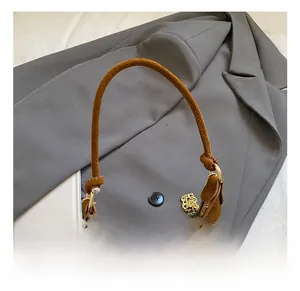 Détail du sac à main en daim marron avec chaîne dorée et finitions métalliques fines