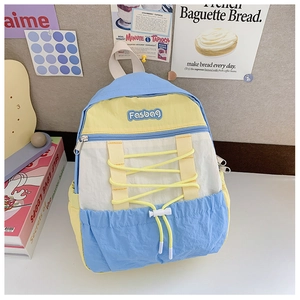 Detail of color-block kids backpack showing blue nylon fabric and yellow elastic drawstring
