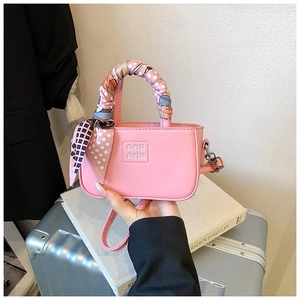 Dettaglio della mini borsa rosa con manico in foulard di seta e dettagli logo a rilievo