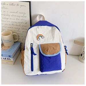 Detail of colorful rainbow embroidery and brown flap pocket on kids lightweight backpack