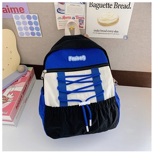 Detail of color-block kids backpack with blue cross-straps and white drawstring buckle