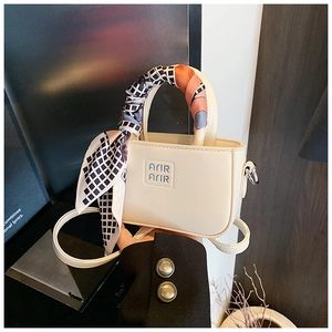 Dettaglio della mini borsa color crema con manico in seta e logo inciso frontalmente