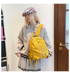 Detail of a bright yellow waterproof nylon backpack with durable dual zippers for kids